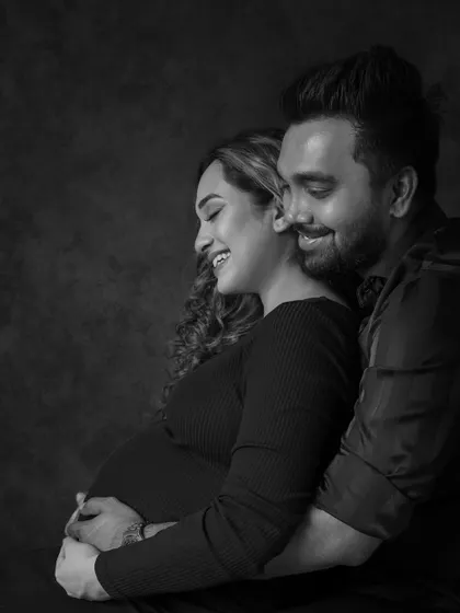 Laughter and love captured in a timeless black and white photo. This candid moment shows the couple sharing a joyful embrace, a perfect memory of their pregnancy journey.
