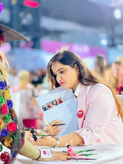 Dipika Parihar carefully evaluating a complex fantasy nail art piece at the Nailathon competition. We teach our students to aim for this level of competitive excellence.