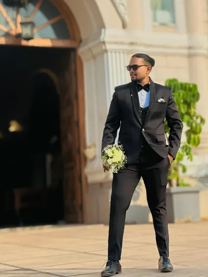Ready to walk down the aisle. Holding a bouquet, this groom looks every bit the part in a classic black tuxedo, available for rent from my collection.