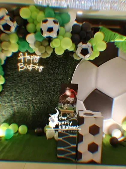 A slightly blurred, artistic shot of the football party backdrop, emphasizing the vibrant green, black, and white colors and the excitement of the theme.