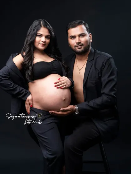 A confident couple's portrait in matching black outfits, looking directly at the camera with a powerful presence.