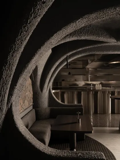 This is a view into the heart of Call Me Ten, a Japanese-inspired restaurant in New Delhi. The design is a study in brutalist poetry, where repeating concrete arches create a rhythmic, cave-like procession, guiding the eye and the body through a narrative of shadow and form.