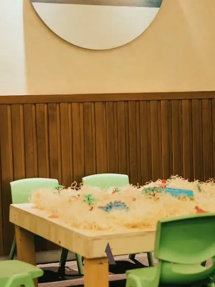 A fun activity station for a "3 Rex" dinosaur-themed party. The sand-filled table lets kids dig for dino fossils, adding an interactive element to the celebration.