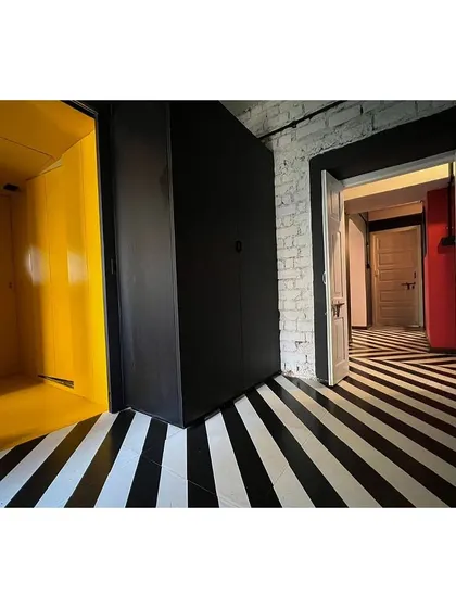 A yellow phone booth-like nook is inserted into the hallway of the co-living space. This intervention creates a semi-private space for calls or quiet moments, adding functional variety to the shared areas.