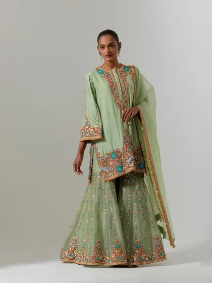 A stunning mint green sharara set with multi-colored embroidery. The flared sharara pants are heavily embellished, making this a true statement piece for a wedding or reception.
