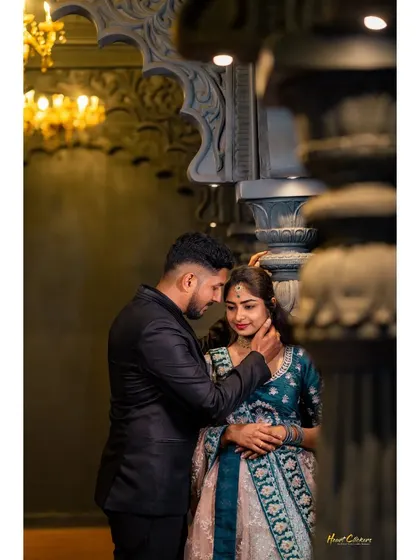 A tender moment between a couple in a grand hall. The groom gently touches the bride's face, creating a deeply emotional and cinematic shot.