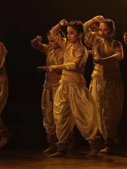 A dramatic moment from a group performance at Varshik Utsav 2024, showcasing creative choreography and lighting.
