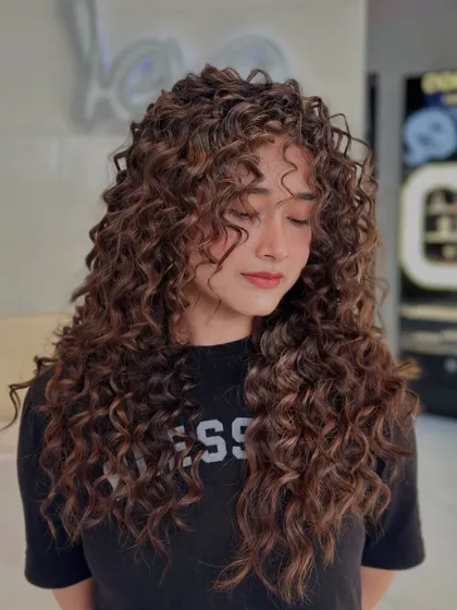 These curls are making their own rules. This shot shows the incredible volume and texture we achieved with a specialized curly cut and style.
