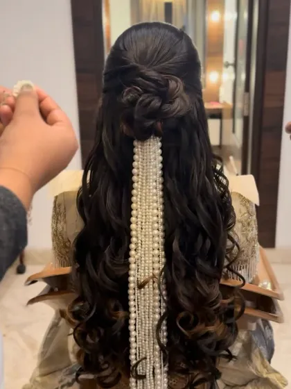 The process of creating a beautiful half-updo, with a pearl accessory being added to the cascading curls.