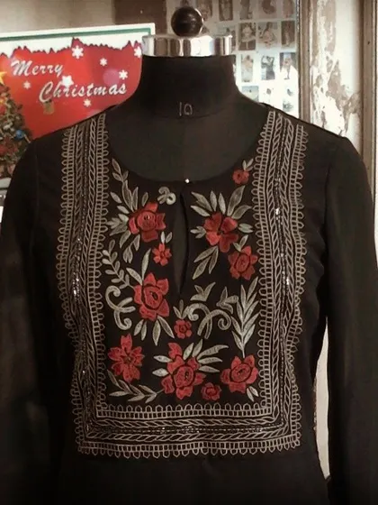 A close-up of a black kurta on a mannequin, showcasing intricate red and silver floral embroidery around the neckline. This piece is a versatile addition to any festive wardrobe.