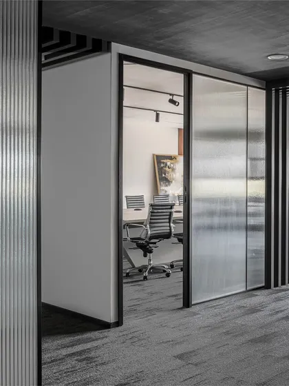 Fluted glass and wood paneling are used to brighten long corridors. The texture of the glass diffuses light beautifully, while the vertical lines of the wood and glass create a sense of rhythm and warmth in a transitional space.