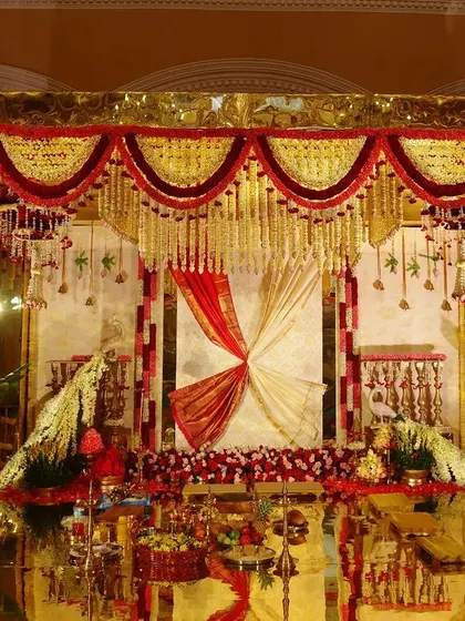 A full view of the magnificent South Indian decor. The entire mandap is built on a golden mirror platform, reflecting the vibrant floral arrangements and creating a mesmerizing, kaleidoscopic effect that celebrates tradition.