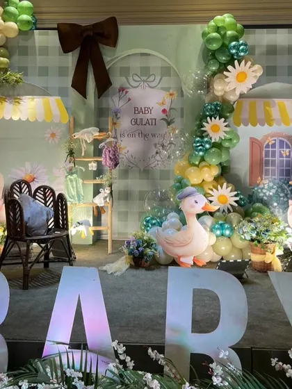 A wide view of the stage setup, with large light-up "BABY" letters and a charming scene featuring duck props and market stall awnings.