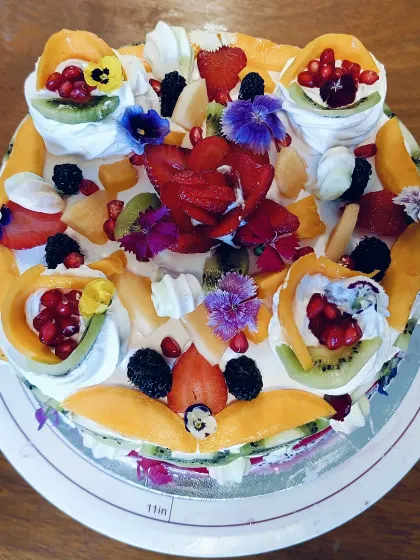Fruit, cream and little flowers cover our summer fruit Pavlova, with colourful toppings arranged across the whole cake.