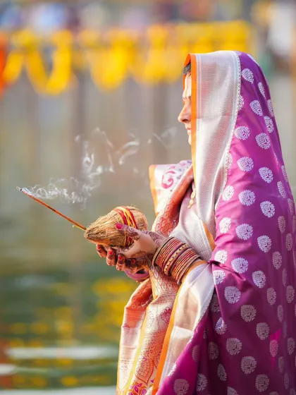 A woman holds an incense stick, the smoke carrying her prayers upwards during Chhath Puja. The festival is a multi-sensory experience of devotion.