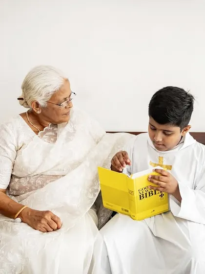 A grandmother shares a special moment with her grandson as he reads from the Bible during his Holy Communion. Capturing intergenerational connections during family events is so important.