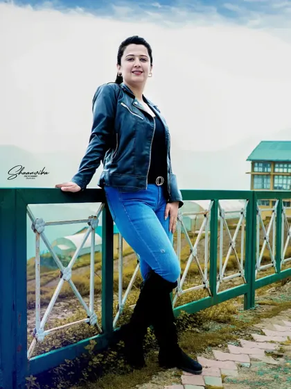 A confident portrait of the bride-to-be in her casual pre-wedding outfit. The outdoor setting with the fence adds a nice compositional element.