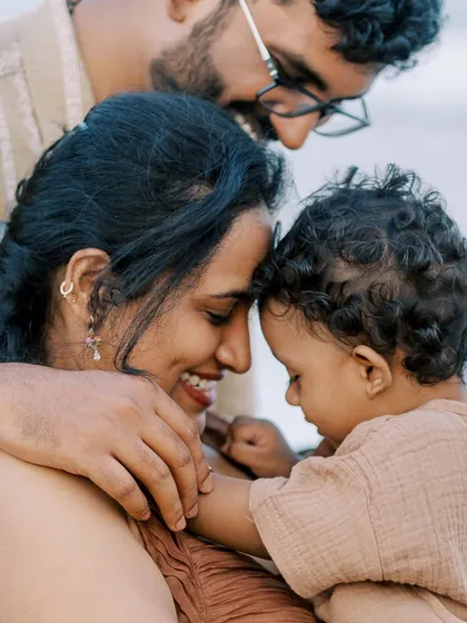 A family sharing a tender moment on the beach. The soft colors and gentle interaction create a beautiful, emotional portrait.