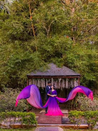 A wide shot showing the scale of a flowing purple and pink gown against the lush green backdrop of our garden.