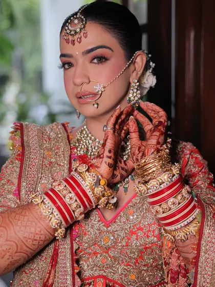 A close-up of the final touches. The traditional red chooda, the intricate henna, and the soft makeup all come together to create the complete picture of a beautiful Indian bride.