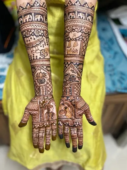 A beautiful example of full-coverage bridal henna with portraits. The design includes swastikas on the fingers and traditional wedding elements on the arms.