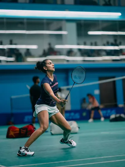 A female player poised to return a shot, demonstrating excellent form and concentration. We create an environment where players of all levels can play their best game.
