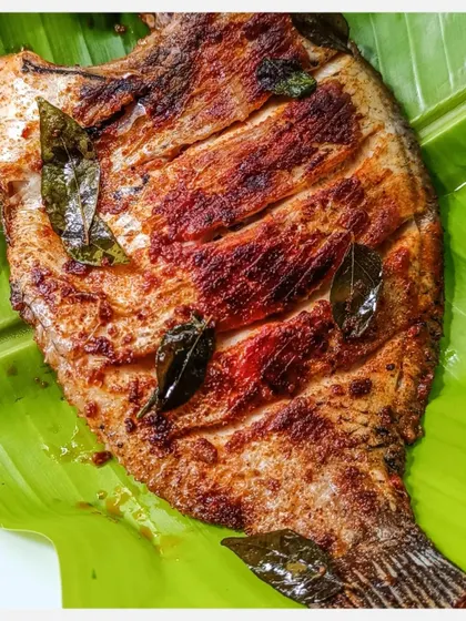 Another close-up of the grilled Karimeen, showcasing the crispy skin and moist flesh of the fish.