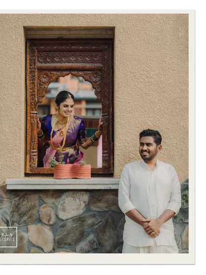A playful portrait of the bride looking out of a traditionally carved window at her groom, creating a lovely story-like image.