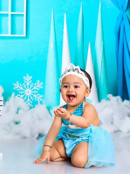 This little snow queen's joyful expression lights up the entire ice palace. It's a perfect shot from a first birthday Frozen-themed session.