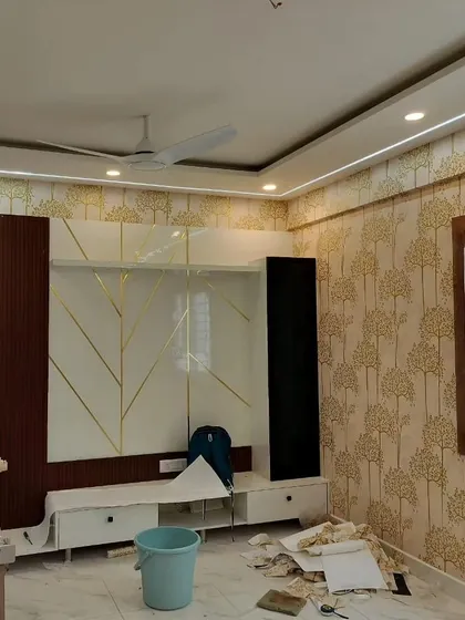 A living room during installation, featuring a tree pattern wallpaper next to a modern TV unit.