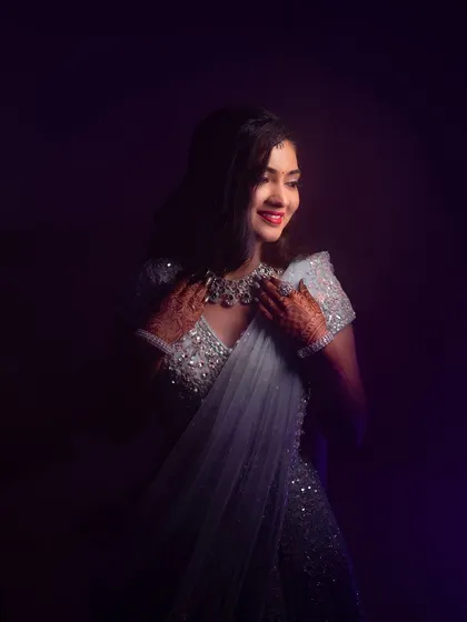 A moody and artistic shot of Rakshita's reception style. The dramatic lighting highlights the sparkle of her lehenga and the elegance of her makeup.