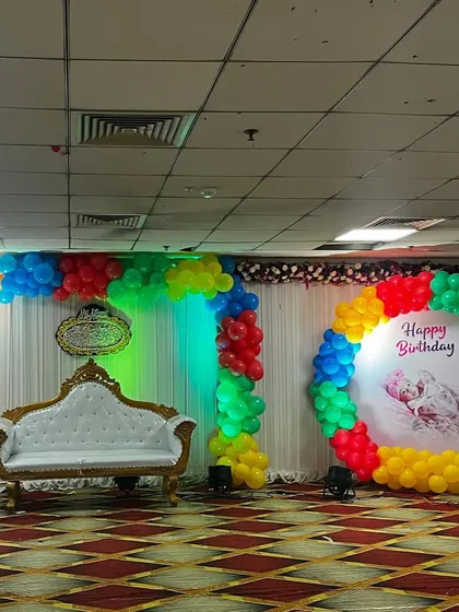 Another view of the rainbow-themed birthday stage, showing the full scope of the vibrant balloon decorations that can brighten up any large hall.