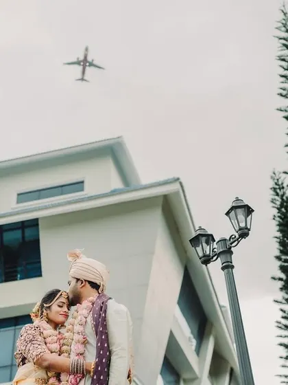 An interesting and unique composition, capturing the couple in a tender moment with an airplane flying overhead, symbolizing their journey ahead.