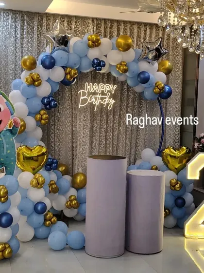 A Cocomelon themed second birthday party decoration. The setup features a balloon arch with a Cocomelon character, a neon sign, cake stands, and a large light-up number '2'.