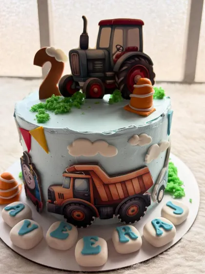 A construction-themed cake for a little one turning two. It features a tractor, a dump truck, and traffic cones for a busy and fun design.