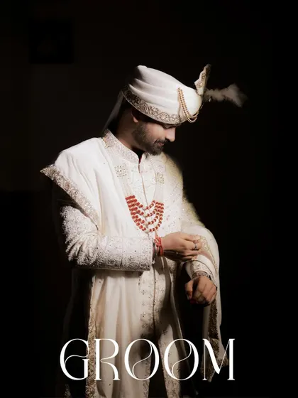 A powerful, full-length portrait of the groom against a dark background. The word 'GROOM' is elegantly overlaid, making this a definitive and timeless image from his wedding day.