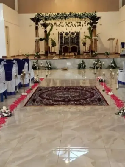 An aisle view of the wedding hall, with the path lined by scattered petals leading up to the magnificent traditional mandap, building anticipation for the ceremony.