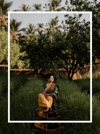 A thoughtful portrait of the bride sitting on a chair in a field of tall grass, framed for a modern look.