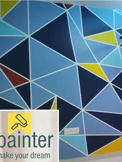 A vibrant geometric wall mural with a triangular pattern in multiple shades of blue, yellow, and red. This type of precision painting is perfect for a modern home, office, or cafe.