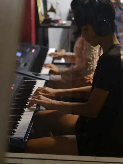 A view through the classroom window of students practicing piano. We foster an environment of shared learning and mutual support.