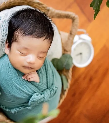 A beautiful overhead shot of a newborn wrapped snugly in a basket. This pose highlights just how tiny and precious they are in their first few weeks.