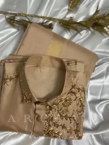 A simple yet elegant groom's outfit. This beige silk kurta has delicate gold floral embroidery on the collar and shoulder, making it a sophisticated choice for any pre-wedding ceremony.