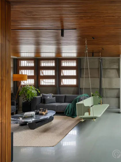 The main living area is designed for comfort and connection. The custom swing, set against a backdrop of concrete and wood, is a focal point that encourages relaxation and family interaction within the open-plan layout.