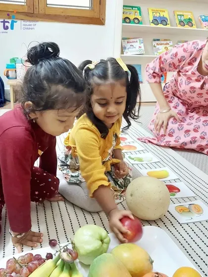 Two girls work together to identify and match fruits. Collaborative learning encourages communication and teamwork among our students.
