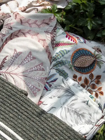 A selection of fabrics from our nature-inspired collections, laid out to show the interplay of different patterns, from bold geometric weaves to hand-drawn botanical motifs.