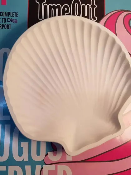 An empty white clam shell dish, highlighting its beautiful, clean lines and texture.