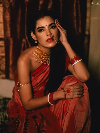 A striking portrait of the model looking directly at the camera. Her confident gaze, combined with the traditional styling, creates a powerful and modern interpretation of a bride.