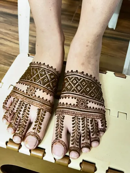 A simple yet elegant foot mehendi design. The pattern features leafy vines on the toes and a delicate band across the top of the foot.