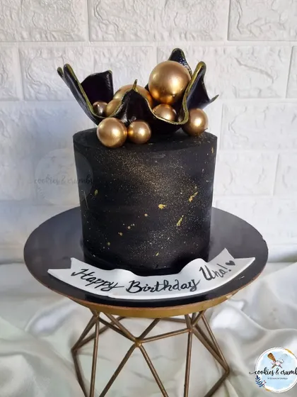 One of my favorite black cakes. This design features a black chocolate sail topper and gold spheres, creating a dramatic and artistic look.