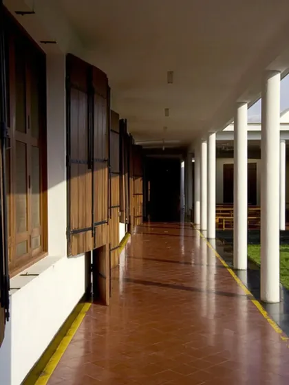 The long, shaded corridor at the Synergy Textiles Factory provides a cool, protected walkway for workers. The design, with its simple columns and traditional wooden shutters, is a modern interpretation of vernacular Indian architecture, adapted for an industrial setting.